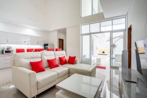 een woonkamer met een witte bank en rode kussens bij Luxury minimalist villa The Toy in Kerobokan