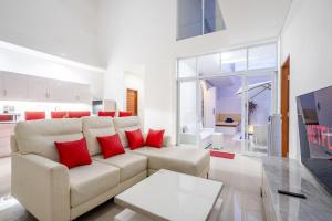 een woonkamer met een witte bank en rode kussens bij Luxury minimalist villa The Toy in Kerobokan