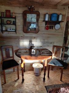 a room with a table and two chairs and a clock at La Cabane du Trappeur in La Bourgonce