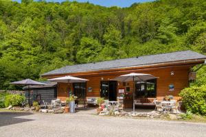 ein Gebäude mit Tischen, Stühlen und Sonnenschirmen in der Unterkunft Auberge Les Myrtilles in Couflens