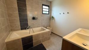 une salle de bains avec baignoire et lavabo dans l'établissement Maison Amalia, à Sainte-Suzanne 23 autres photos