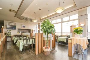 Un restaurante con mesas y sillas y una planta. en Tendo Central Hotel, en Tendō