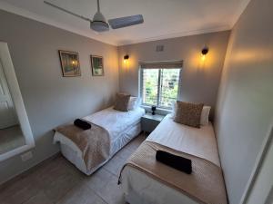 a bedroom with two beds and a window at Unit 40 Chakas Rock Chalets in Ballito +16 photos