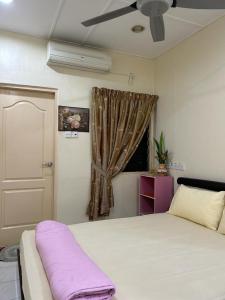 a bedroom with a bed with a purple blanket on it at Taman Gerik Homestay in Gerik