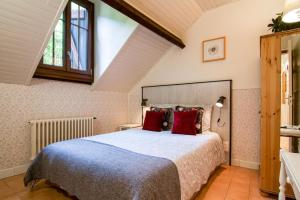 ein Schlafzimmer mit einem großen Bett mit roten Kissen in der Unterkunft Auberge Les Myrtilles in Couflens