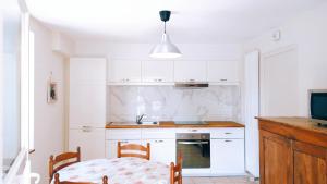 Gîte Chez Julie - Clima - Parking في سارلا لا كانيدا: مطبخ بدولاب بيضاء وطاولة وتلفزيون