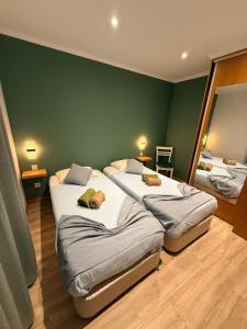 zwei Betten in einem Zimmer mit grüner Wand in der Unterkunft Casa Trevo de 4 Folhas in Furnas