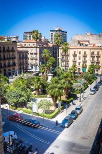 una strada di città con automobili, palme e edifici di Liberty Suites a Palermo