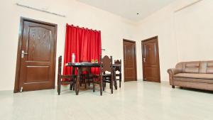 a living room with a table and chairs and a red curtain at 10 mins to Rock Beach-Sérénade Homestay in Puducherry