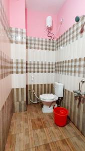 a bathroom with a toilet and a red bucket at 10 mins to Rock Beach-Sérénade Homestay in Puducherry