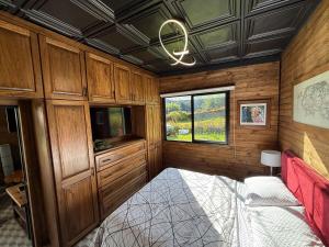 1 dormitorio con cama, armarios de madera y ventana en Mini House Reserva Natural, en Guarne
