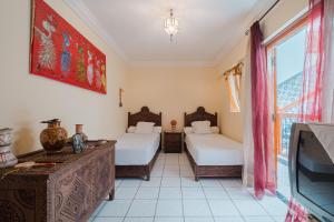 马拉喀什Riad Palm Oasis Marrakech的一间有两张床和一台电视的房间 更多32张照片