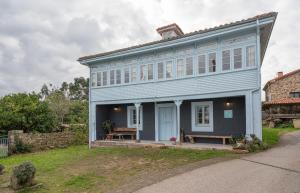 une maison bleue avec un banc devant elle dans l'établissement Casona Azul Llue - Asturias Vacations, à Colunga