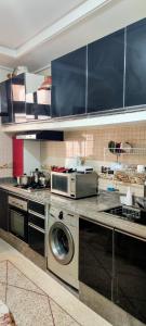 a kitchen with a washing machine and a microwave at Appartement meublé à louer in Meknès