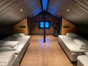 two beds in a room with wooden walls and wood floors at Villa Hulu in Broaryd