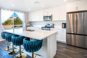 a kitchen with white cabinets and a large island with blue bar stools at #Marbella Lane - Desert Dream Pool Spa & Games in Desert Hot Springs