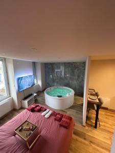 a large bathroom with a tub and a bed at La petite suite Ponote in Le Puy en Velay