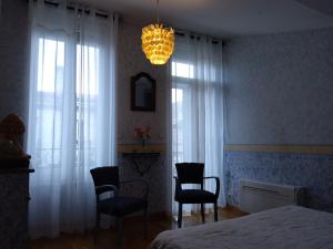 een slaapkamer met een bed en 2 stoelen en een kroonluchter bij Chambre La Petite Pause - Bordeaux in Bordeaux