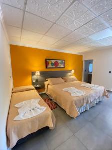 two beds in a room with yellow walls at Alto Valle in Nono
