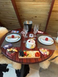 a wooden table with plates of food and wine glasses at Chalés Mirante da Serra PB in Serra da Raiz