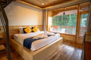 a bed in a room with a large window at Hide-In Kasol in Kasol