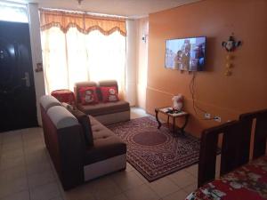 un salon avec un canapé et une télévision au mur dans l'établissement Sultana de los Andes Apartment, à Riobamba