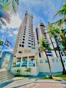 累西腓Valor Imbatível ! Flat Frente Mar com Enxoval completo的一栋高楼，前面种着棕榈树。 更多18张照片