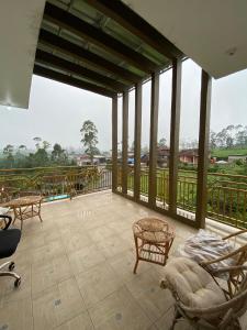 a room with a balcony with chairs and tables at Villa Pangalengan in Palayangan