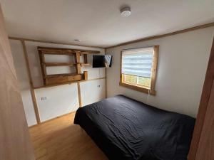 ein kleines Schlafzimmer mit einem Bett und einem Fenster in der Unterkunft cabañas fariña in Llanquihue