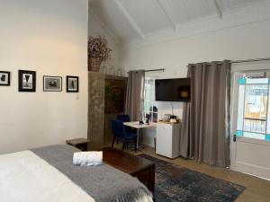 Un dormitorio con una cama, una mesa y un escritorio. en Regalia Suites, en Kraaifontein