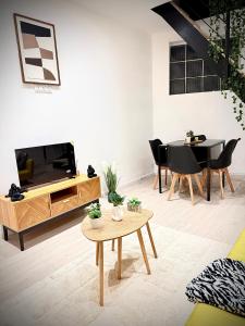 un salon avec une télévision, une table et des chaises dans l'établissement Écrin de Roye, à Roye