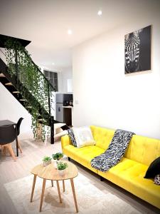 un salon avec un canapé jaune et une table dans l'établissement Écrin de Roye, à Roye