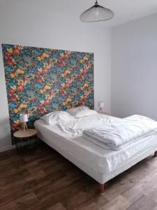 a bed in a bedroom with a floral wall at Étape Douessine in Doué-la-Fontaine +1 photo