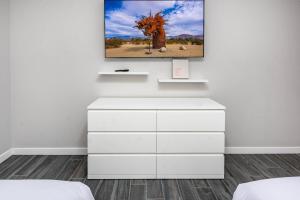 a white bedroom with a tv on a wall at #Marbella Lane - Desert Dream Pool Spa & Games in Desert Hot Springs