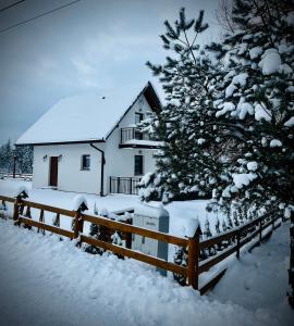 a house covered in snow next to a fence at ORAWSKA CHATA - domek z balią pod Babią Górą in Zubrzyca Górna