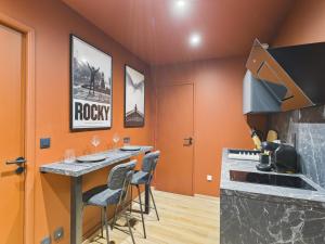 a kitchen with orange walls and a counter with stools at Ciné-Ponot in Le Puy en Velay