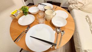 a wooden table with white plates and utensils on it at Good One Awaji Accessia 401 in Osaka