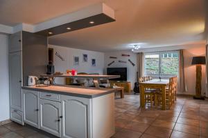 a kitchen with white cabinets and a dining room with a table at Le Cerisier in Erde