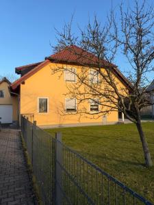 a yellow house with a fence in front of it at MainZeit Albertshofen 2 Zimmerwohnung Parkplatz 