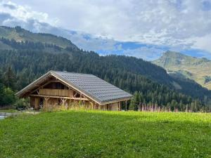 une grange dans un champ avec des montagnes en arrière-plan dans l'établissement Grand Chalet au Praz de Lys, à Taninges 17 autres photos