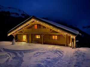 une cabane en rondins dans la neige la nuit dans l'établissement Grand Chalet au Praz de Lys, à Taninges