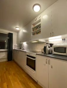 a kitchen with white cabinets and a microwave at Wesfield Private in Solna