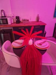 een eetkamer met een tafel met borden en een rood licht bij Love Room romantique avec jacuzzi - Arles centre in Arles