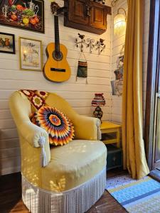 Zimmer mit einem Stuhl und einer Gitarre an der Wand in der Unterkunft Roulotte Belle des Prés in Sigalens