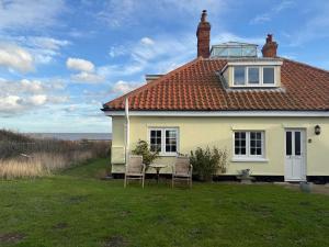 une maison blanche avec des chaises et une table dans la cour dans l'établissement Cottage on remote wild coast, à Bawdsey