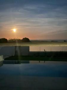 a sunset over a body of water with the sun setting at Blue Aura Beach villa Larnaca in Perivolia +100 photos