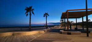 a boardwalk with palm trees and the ocean at night at Location Mobilhome in Narbonne-Plage