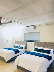 two beds in a room with blue and white at LaPoch Guesthouse in Durban