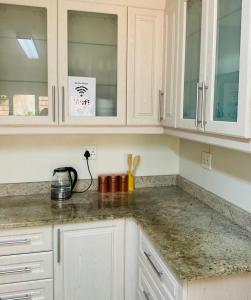 a kitchen with white cabinets and a counter top at LaPoch Guesthouse in Durban +32 photos