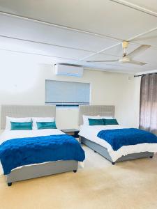 two beds in a bedroom with blue sheets at LaPoch Guesthouse in Durban